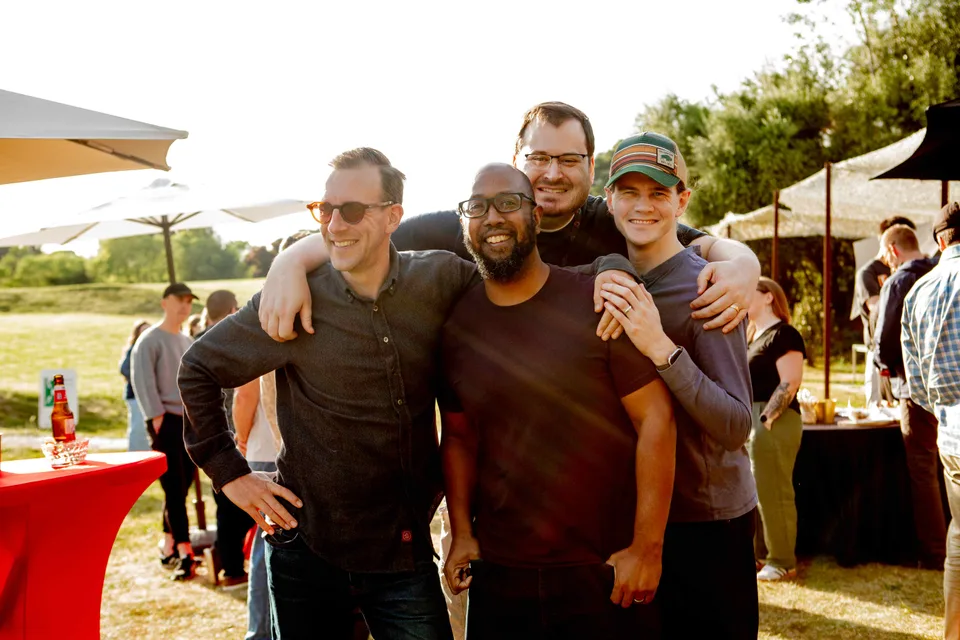 Four teammates with arms around each other, grinning for the camera